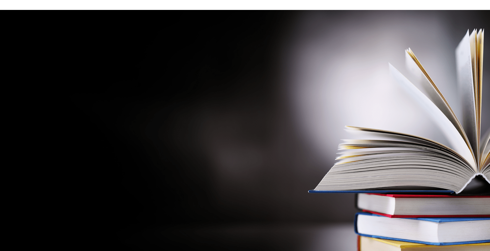 A composition with an open hardcover book lying on a stack of other books 